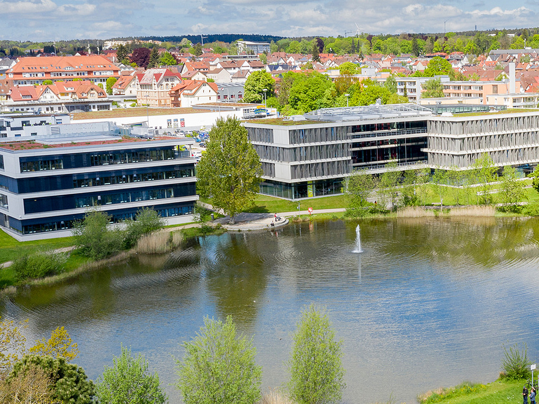 Zentrale der vivida bkk Bild mit See im Vordergrund und im Hintergrund die Zentrale der vivida bkk sichtbar